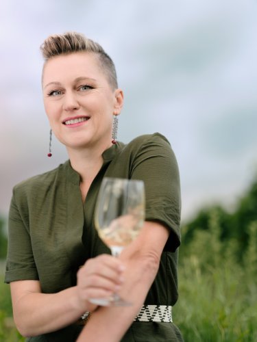 Národní sommelierka Klára Kollárová stojí se skleničkou vína na vinici