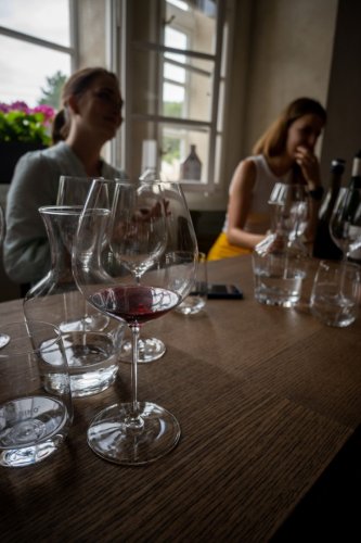 Sklenice zn. Riedel podtrhnou dojem z ochutnávaných vín (za foto děkujeme: Víťa Špičan @vitaspican) Sklenice zn. Riedel stojící na stole během ochutnávky vín, v pozadí degustující návštěvníci vinařství